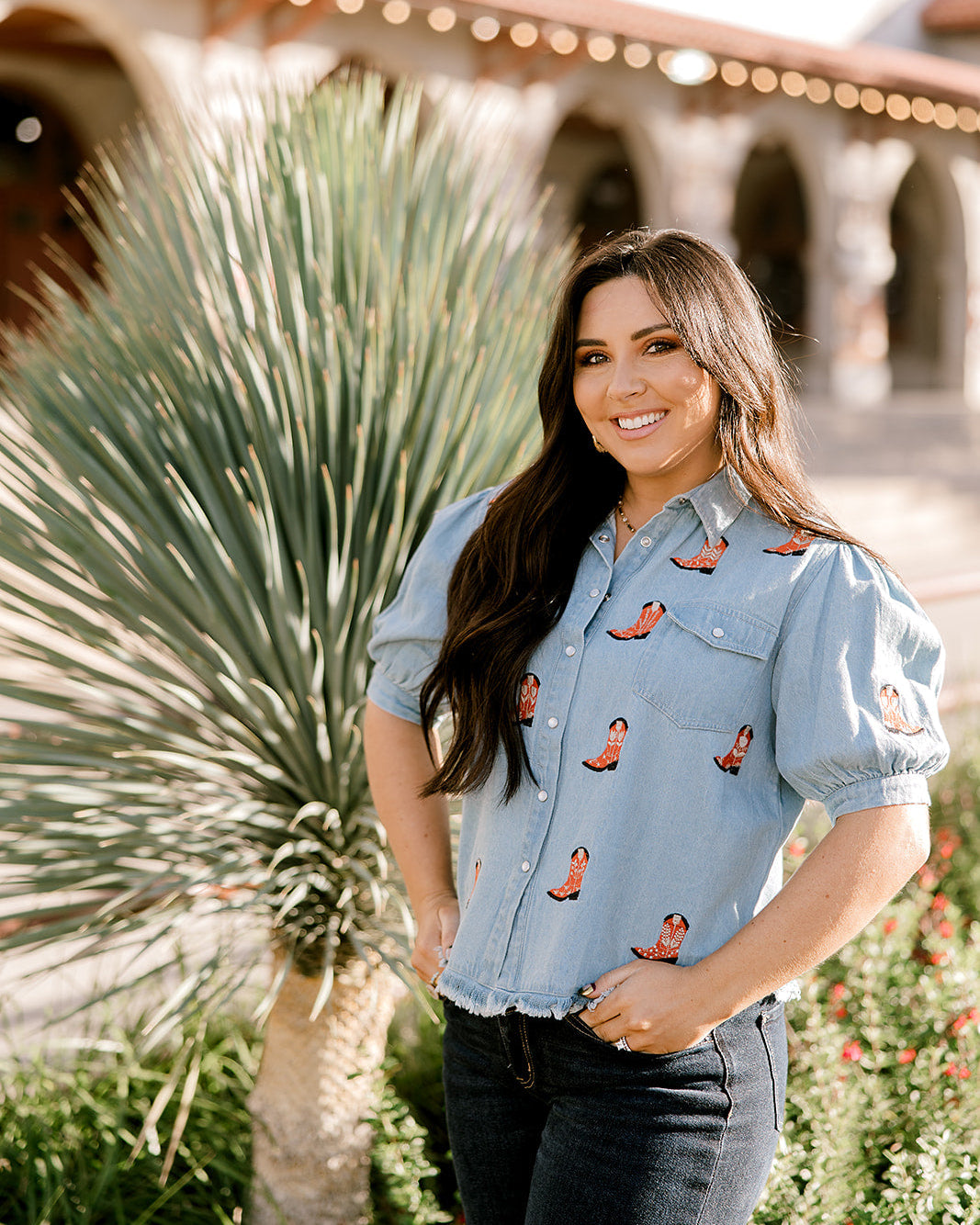 Women wearing a denim top with red boots embroidered on it outdoors. 