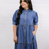 Woman wearing a blue denim dress against a white background