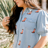 Women wearing a denim top with red boots embroidered on it outdoors. 