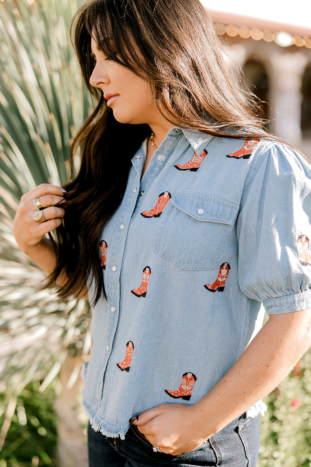 Women wearing a denim top with red boots embroidered on it outdoors. 