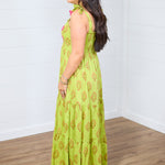Woman with dark hair standing in a side profile position wearing the Addison Maxi Dress against a white background. The focal point of this image is the side of the dress, emphasizing the graphics and the sleeveless straps. 