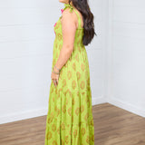 Woman with dark hair standing in a side profile position wearing the Addison Maxi Dress against a white background. The focal point of this image is the side of the dress, emphasizing the graphics and the sleeveless straps. 