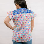 Women wearing a colorful top with blue ebroidery on the top showing the back on a white background 