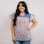 Women wearing a colorful top with blue ebroidery on the top showing the front on a white background 