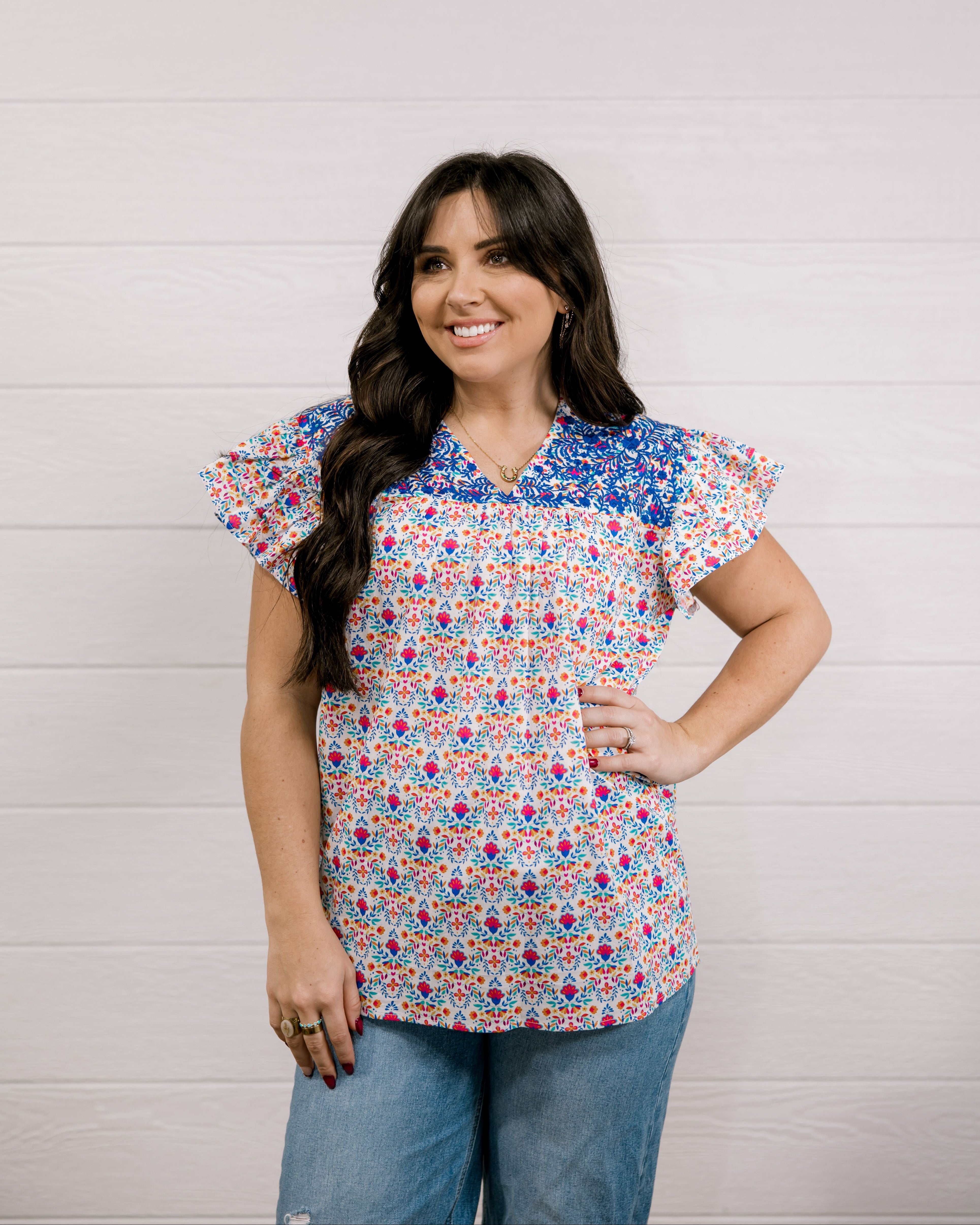 Women wearing a colorful top with blue ebroidery on the top showing the front on a white background 