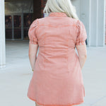 Woman with blonde hair wearing short-sleeve burnt orange midi dress. 