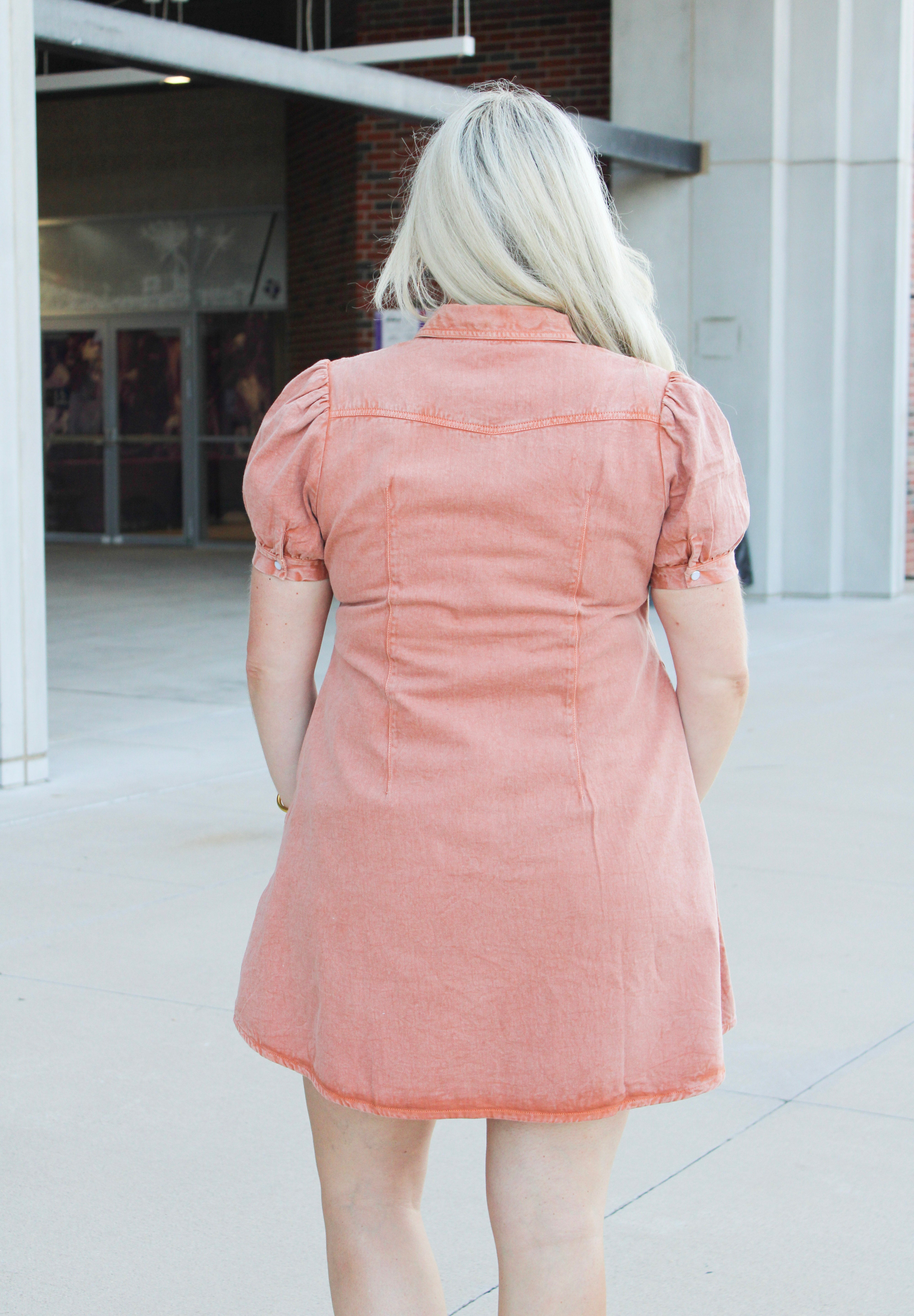 Woman with blonde hair wearing short-sleeve burnt orange midi dress. 