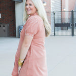 Woman with blonde hair wearing  a burnt orange midi dress.