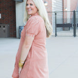 Woman with blonde hair wearing  a burnt orange midi dress.