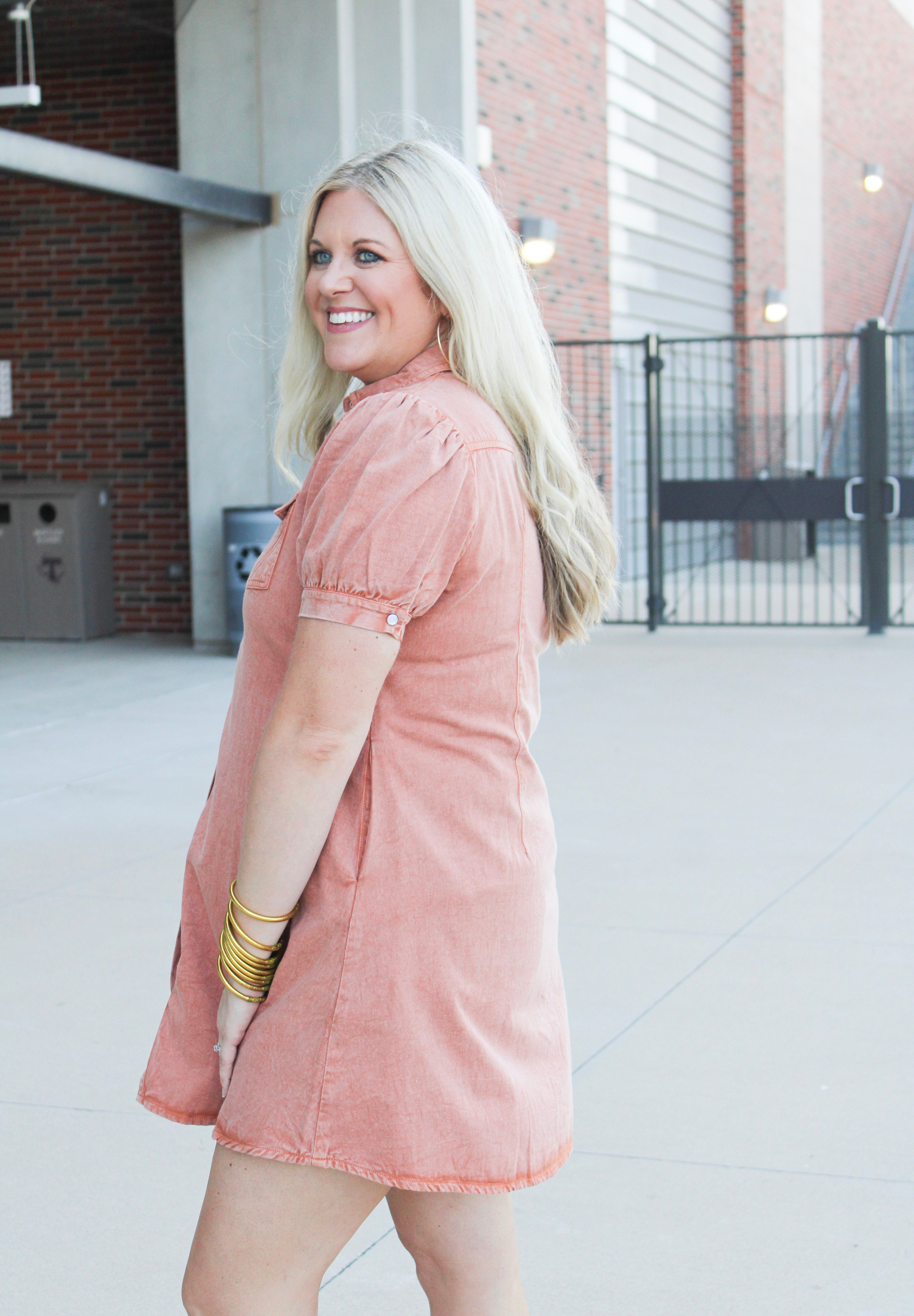 Woman with blonde hair wearing  a burnt orange midi dress.