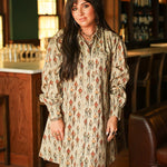 Woman with dark hair wearing a midi long-sleeve dress with cowboy graphics. Model paired this dress with brown and white booties. 