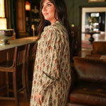 Woman with dark hair wearing a midi long-sleeve dress with cowboy graphics. Model paired this dress with brown and white booties. 