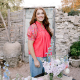 Women wearing coral top in garden.