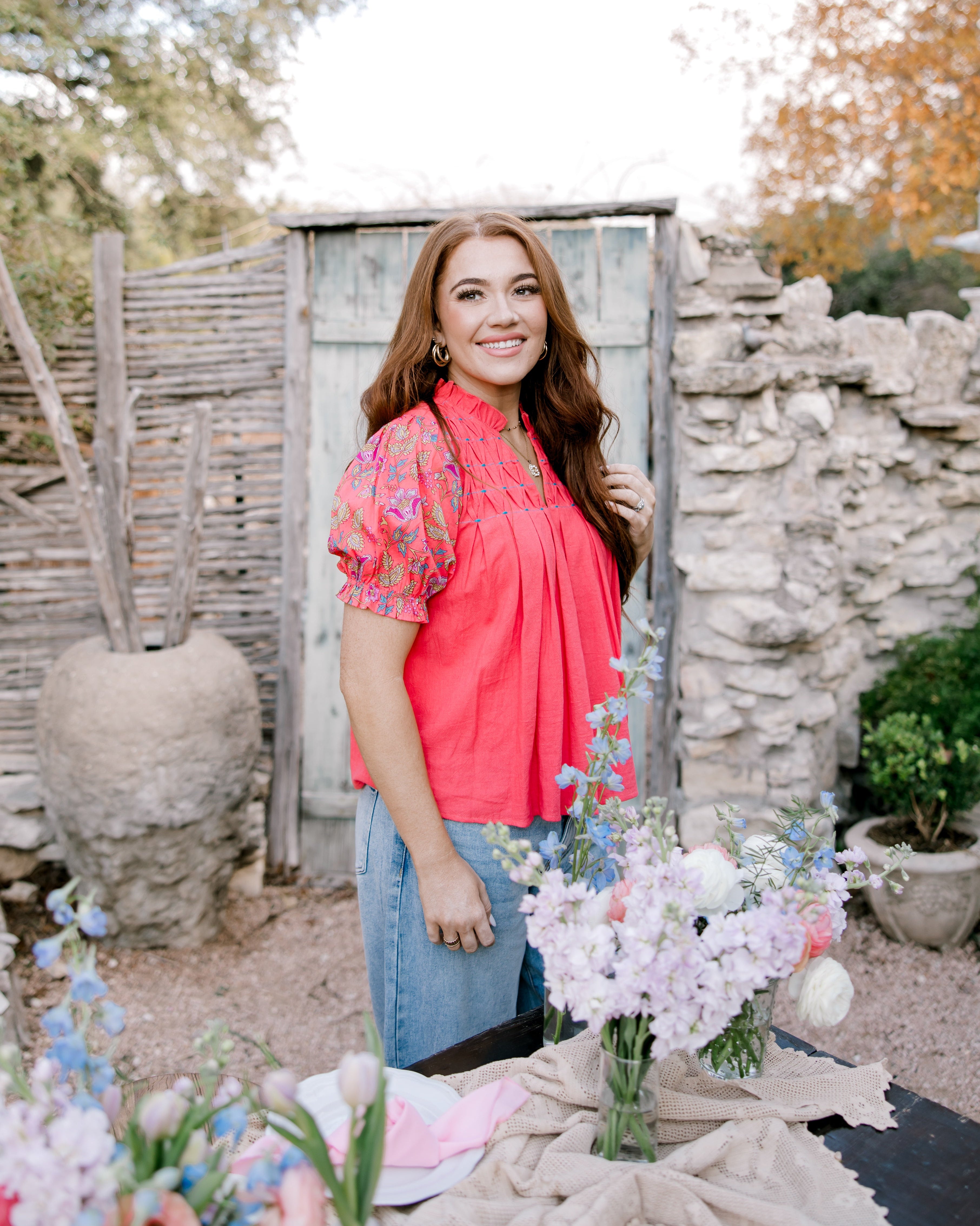 Women wearing coral top in garden.