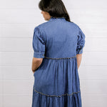 Woman wearing a blue denim dress against a white background