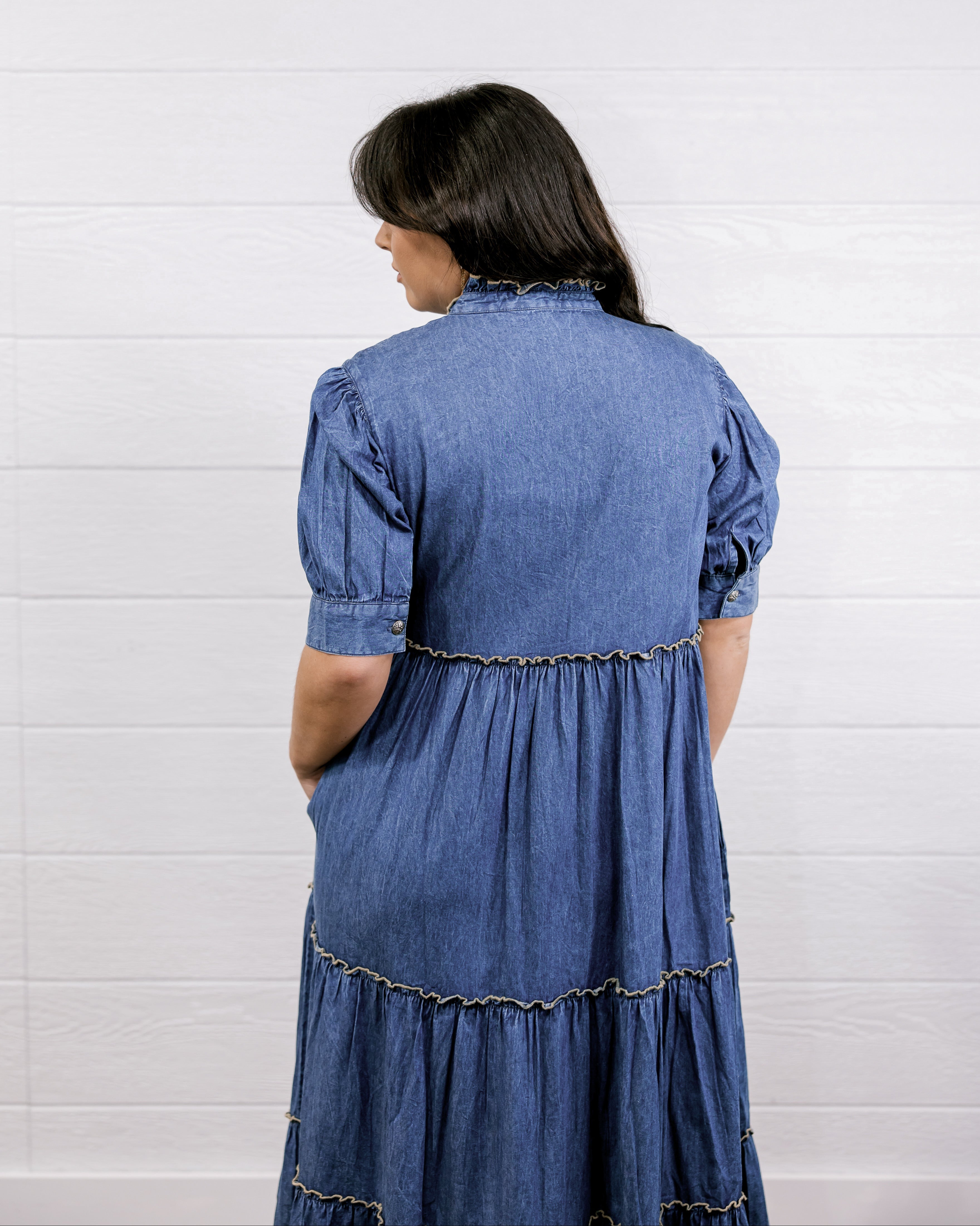 Woman wearing a blue denim dress against a white background