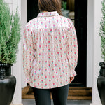 Woman with dark hair wearing a long-sleeve silky top with nutcracker graphics. Model paired this top with faux leather leggings. 