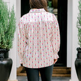 Woman with dark hair wearing a long-sleeve silky top with nutcracker graphics. Model paired this top with faux leather leggings. 