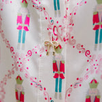 Woman with dark hair wearing a long-sleeve silky top with nutcracker graphics. Model paired this top with faux leather leggings. 