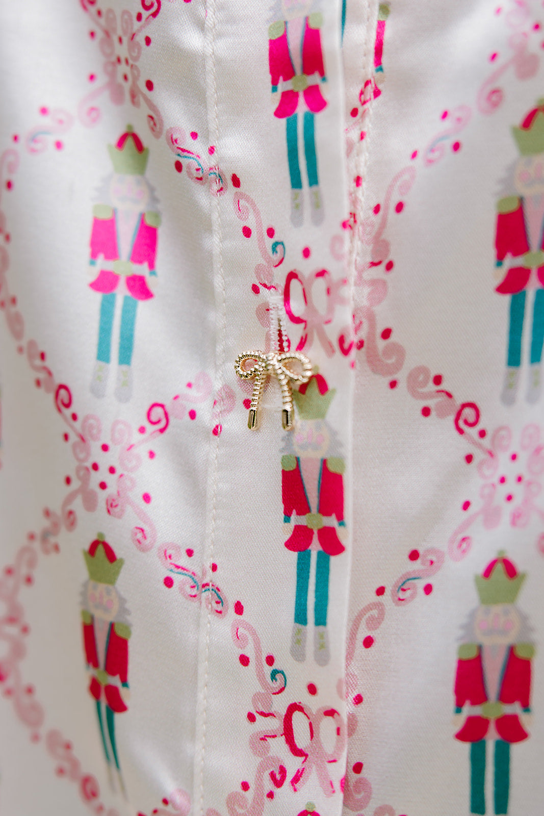 Woman with dark hair wearing a long-sleeve silky top with nutcracker graphics. Model paired this top with faux leather leggings. 