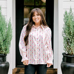 Woman with dark hair wearing a long-sleeve silky top with nutcracker graphics. Model paired this top with faux leather leggings. 