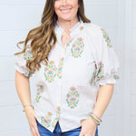 Woman with dark hair wearing the Courtney Top in a front profile with a white background. She paired the top with dark-wash denim shorts.
