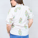 Woman with dark hair showing the Courtney Top in a back profile position against a white background. She paired the top with dark-wash denim shorts. 