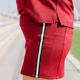Woman standing in a side profile position wearing the Daisy Top and Jane skirt at a football field. The image is in deep focal length, giving a better look at the pattern detail, striping down side of the skirt as well as length of skirt. 
