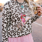 Person wearing a leopard print sweater with colorful accessories in an urban setting