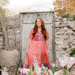 Women wearing a mixed media maxi dress that buttons down the front in a garden. 