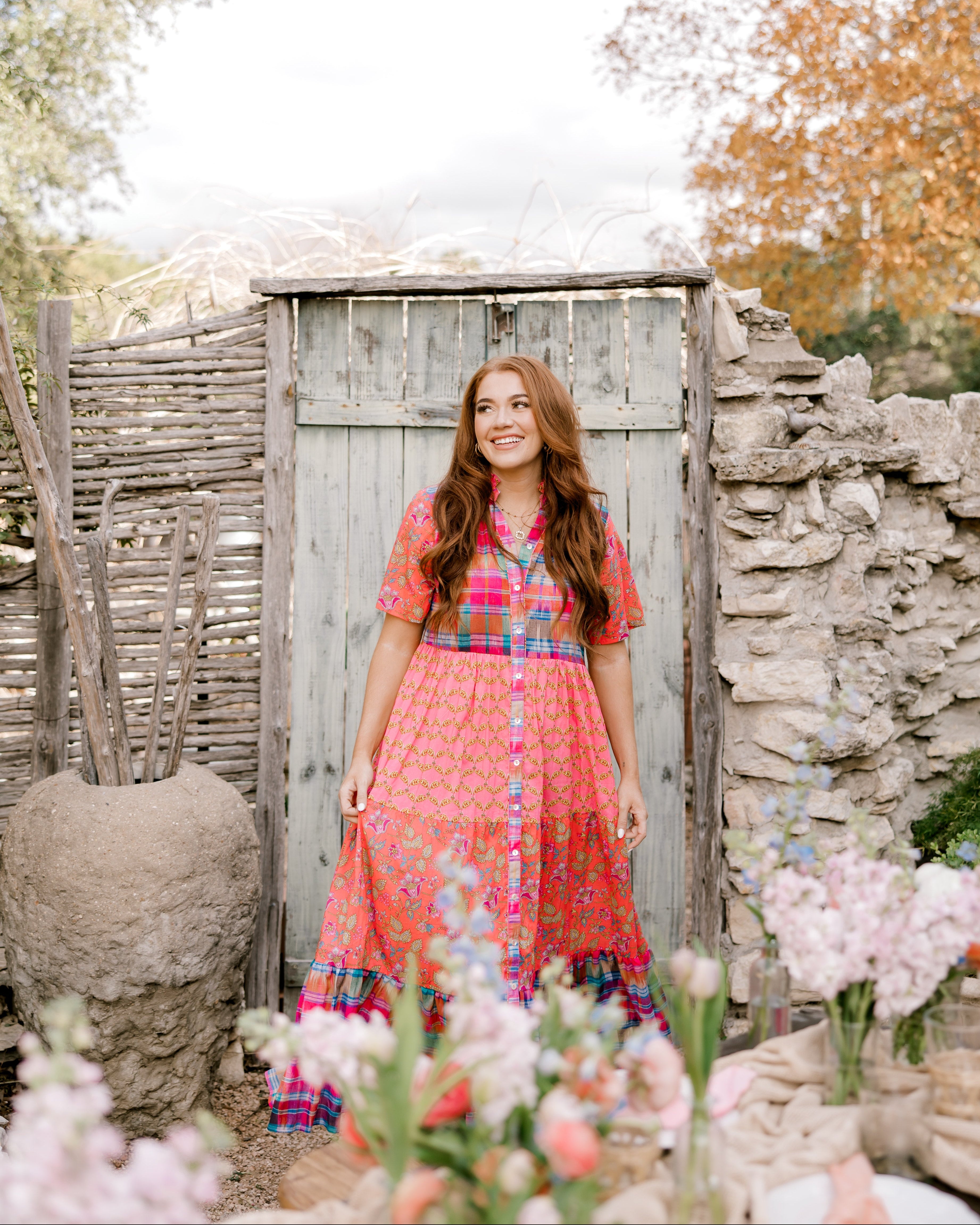 Women wearing a mixed media maxi dress that buttons down the front in a garden. 
