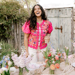 Women wearing a bright colored vest in a garden. 