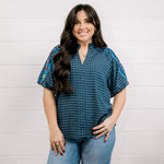 Women wearing a navy shirt with embroidery on the sleeves with a slit V neck against a white background showing the front 