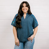 Women wearing a navy shirt with embroidery on the sleeves with a slit V neck against a white background showing the front 