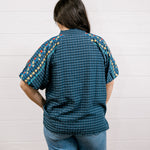 A women wearing a navy top showing the back and fit with detailed embroidery on a white background 