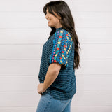 Women wearing a navy shirt showing the side and the detailed embroidery on the sleeve on a white background 