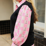 Woman with blonde hair wearing a button-down long-sleeve with black and pink boots graphics on a pink & white checkered background. the model paired this top with dark-wash denim jeans. 