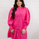 Woman wearing a bright pink eyelet dress against a white background