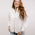 Woman wearing a white shirt and blue jeans against a plain background