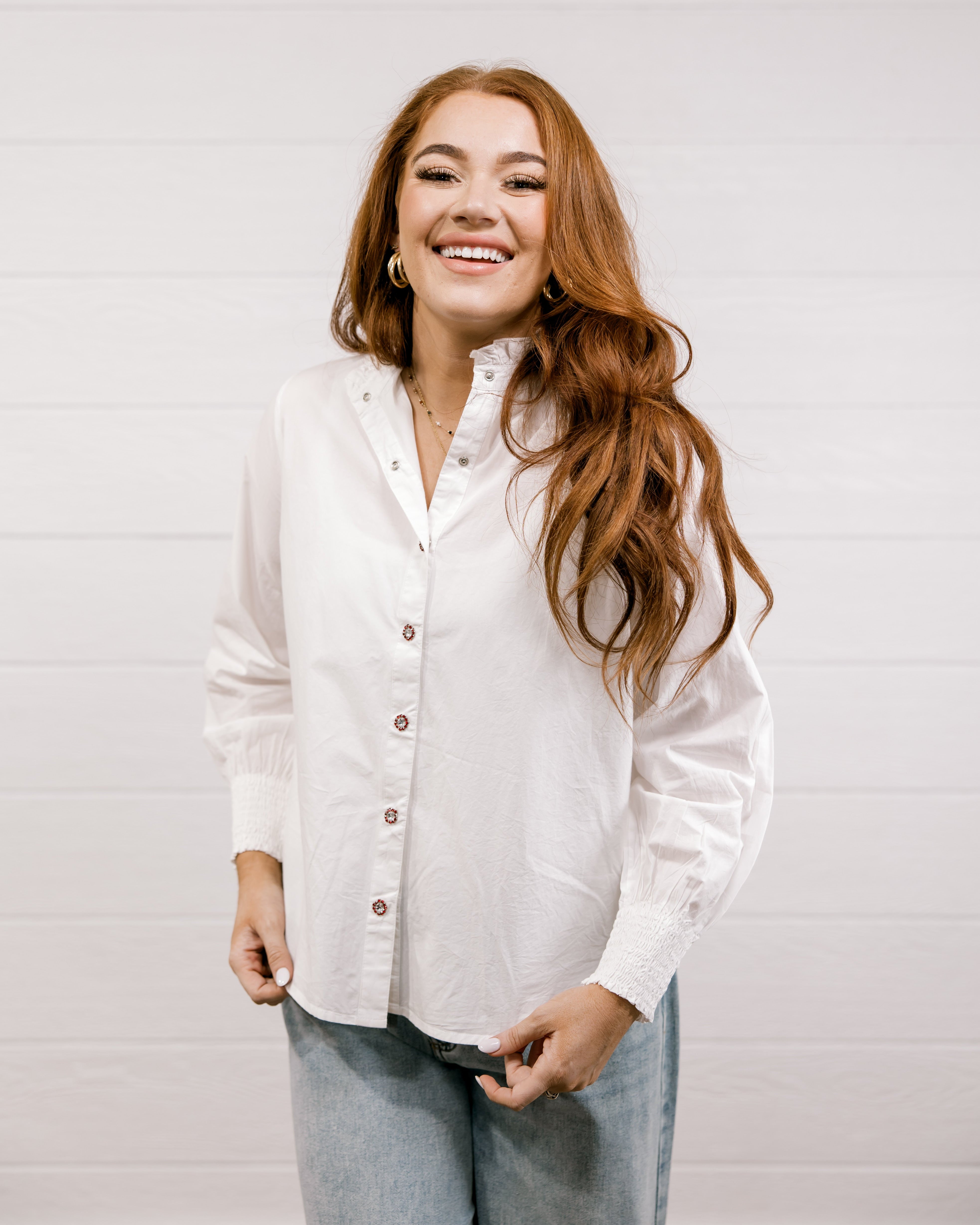 Woman wearing a white shirt and blue jeans against a plain background