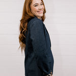 Side view women wearing a denim blazer with leopard lining in front of a white wall.