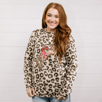 Woman wearing a leopard print sweater with a graphic design against a light wooden panel background