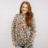 Woman wearing a leopard print sweater with a graphic design against a light wooden panel background