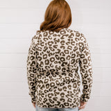 Person wearing a leopard print sweater against a white background