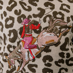 Embroidered design of a person riding a horse on a leopard print background