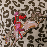 Embroidered design of a person riding a horse on a leopard print background