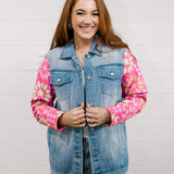Woman wearing a denim jacket with colorful quilted patchwork sleeves against a white background