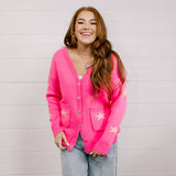 Woman wearing a bright pink cardigan with star patterns against a white background