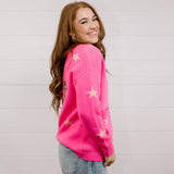 Side view of Woman wearing a bright pink cardigan with star patterns against a white background