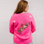 Back view of Woman wearing a bright pink cardigan with star patterns against a white background